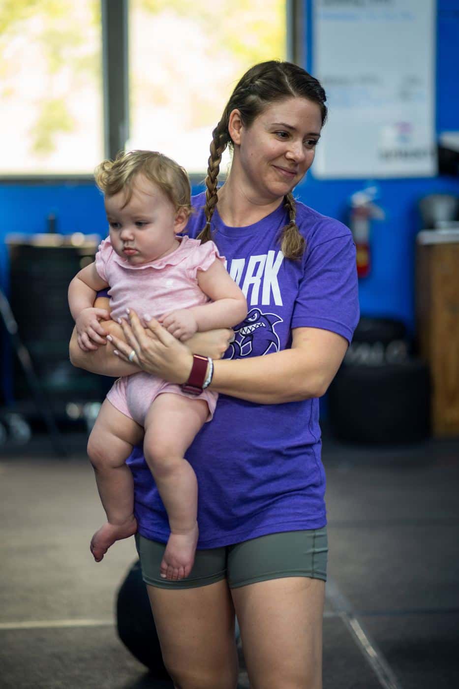A mom holding her baby on her hip between sets