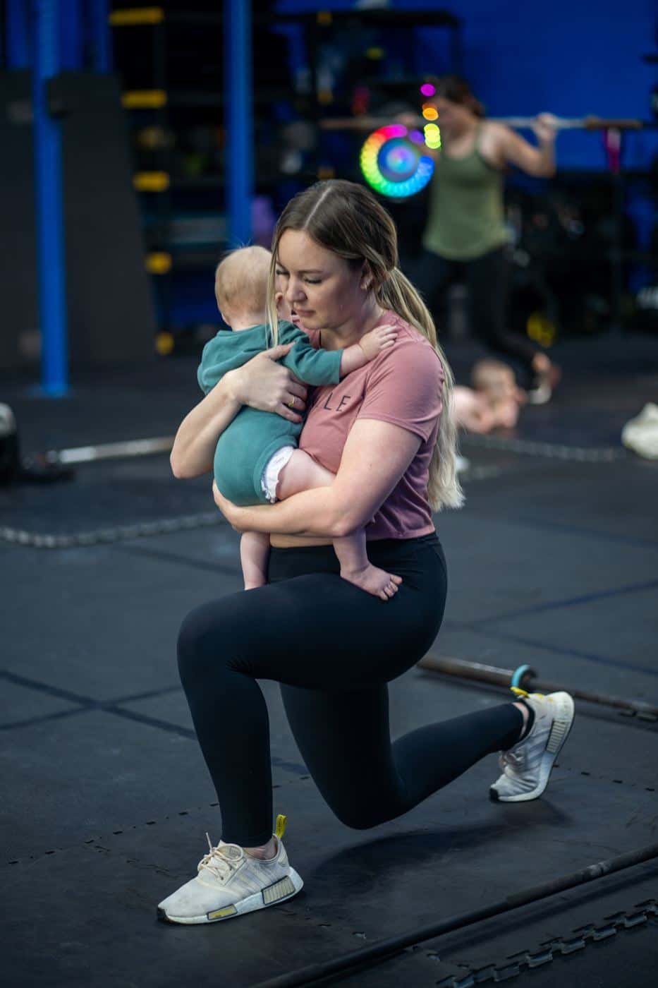 A mom lunging with her baby held against her chest