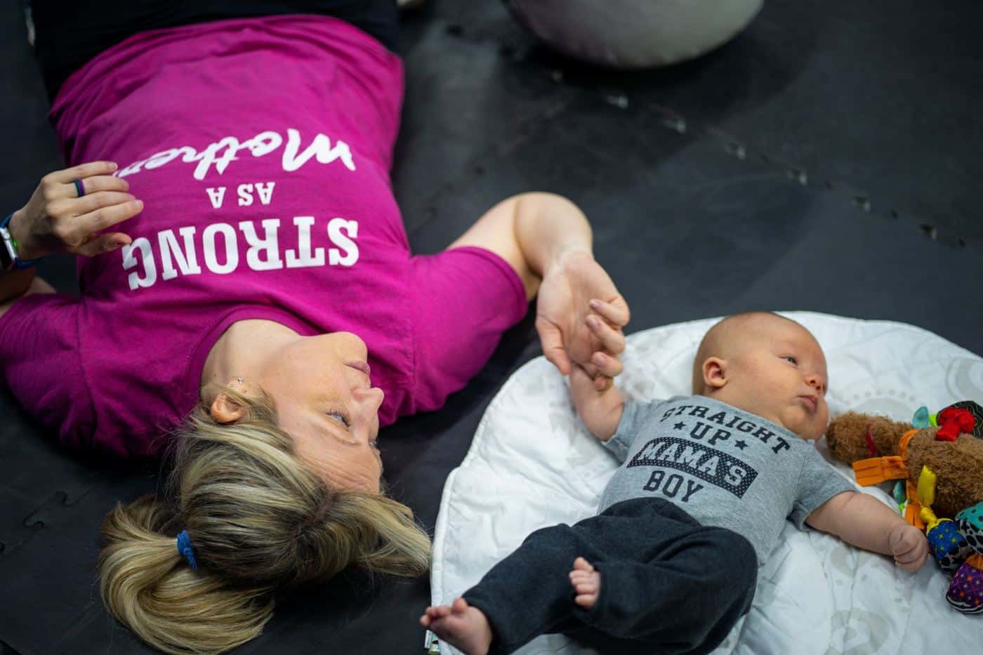 A mom lying on the floor next to her baby during class